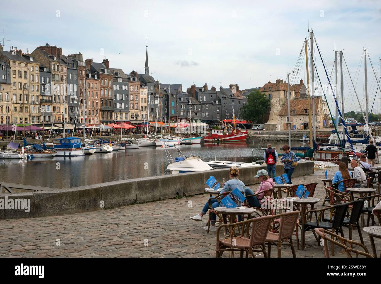 30.08.2024, Francia, Normandia, Honfleur - barche sul Quai Sainte-Catherine e persone in via Cafè nel vecchio porto, Vieux Bassin, nel pict Foto Stock