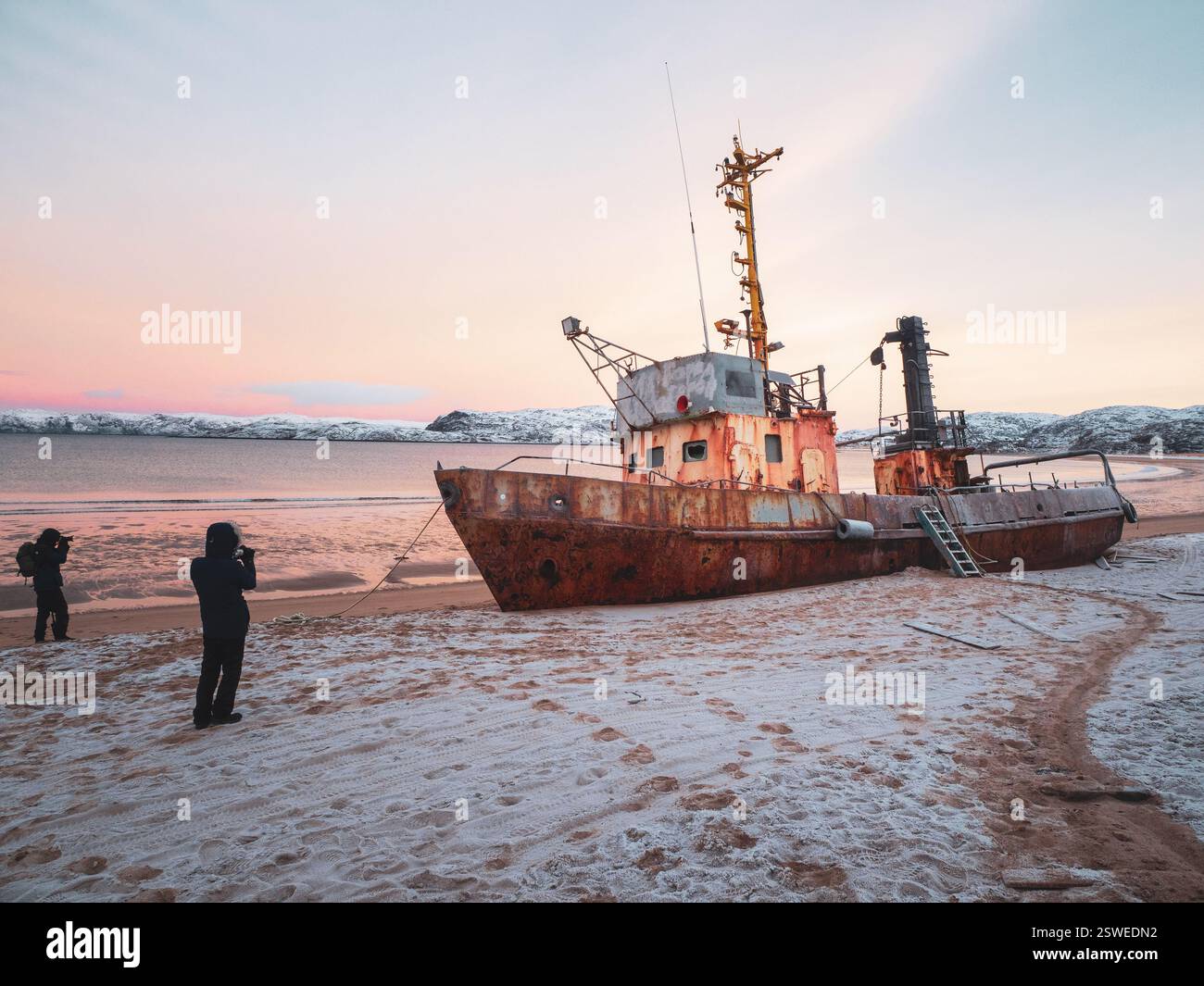 I fotografi scattano foto di una nave bagnata sulla costa dell'oceano Artico da una tempesta Foto Stock