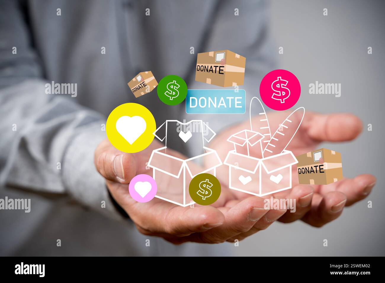 Mani con lettere che scrivono parole. Uomo che tiene una scatola con vestiti da donare davanti al muro. Monete monetarie, responsabilità sociale e concetto di donazione Foto Stock