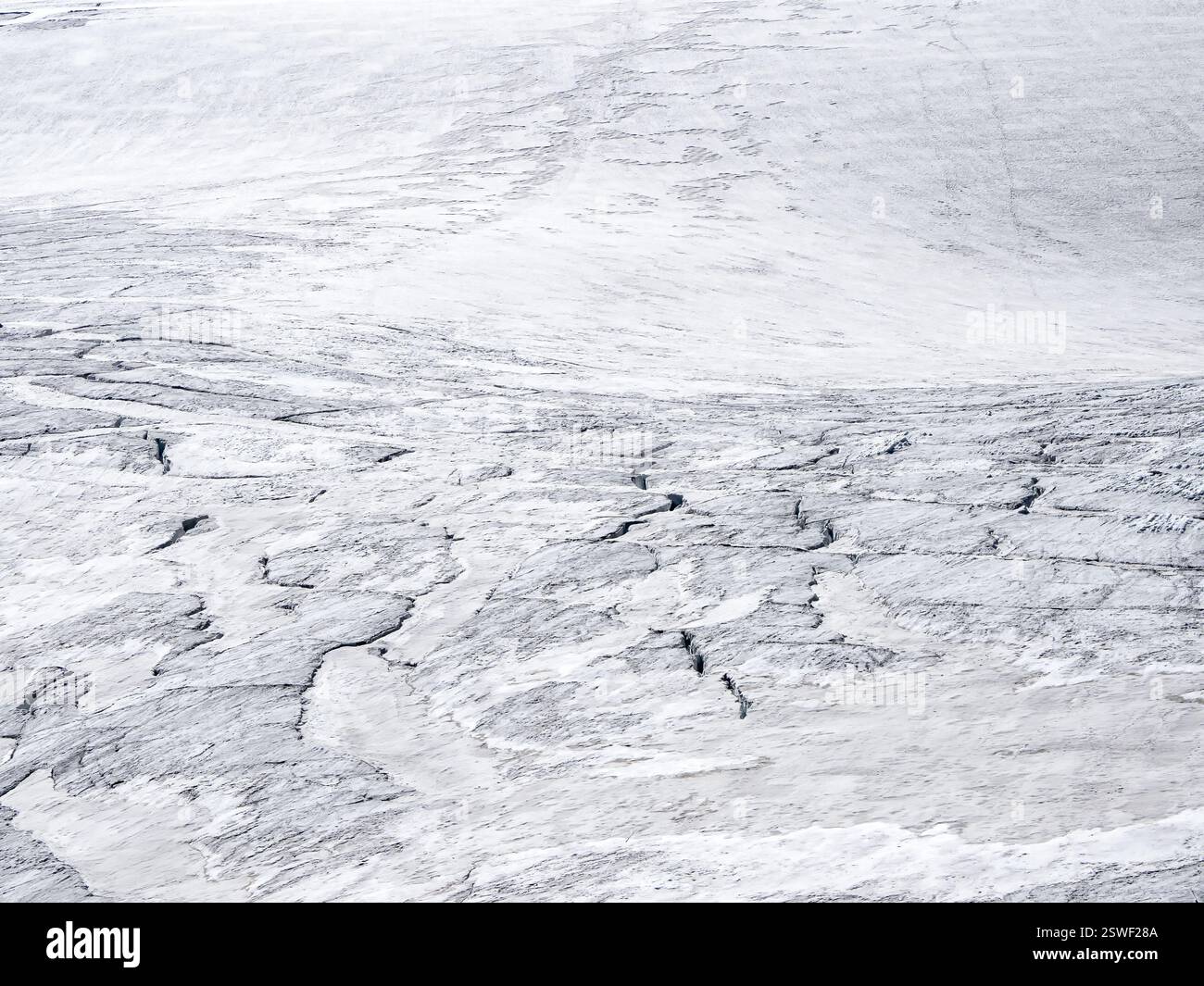 La consistenza della neve bianca, il chiaroscuro bianco. Sfondo naturale minimo di parete ghiacciata con crepe e graffi di ghiaccio dal ghiacciaio Foto Stock