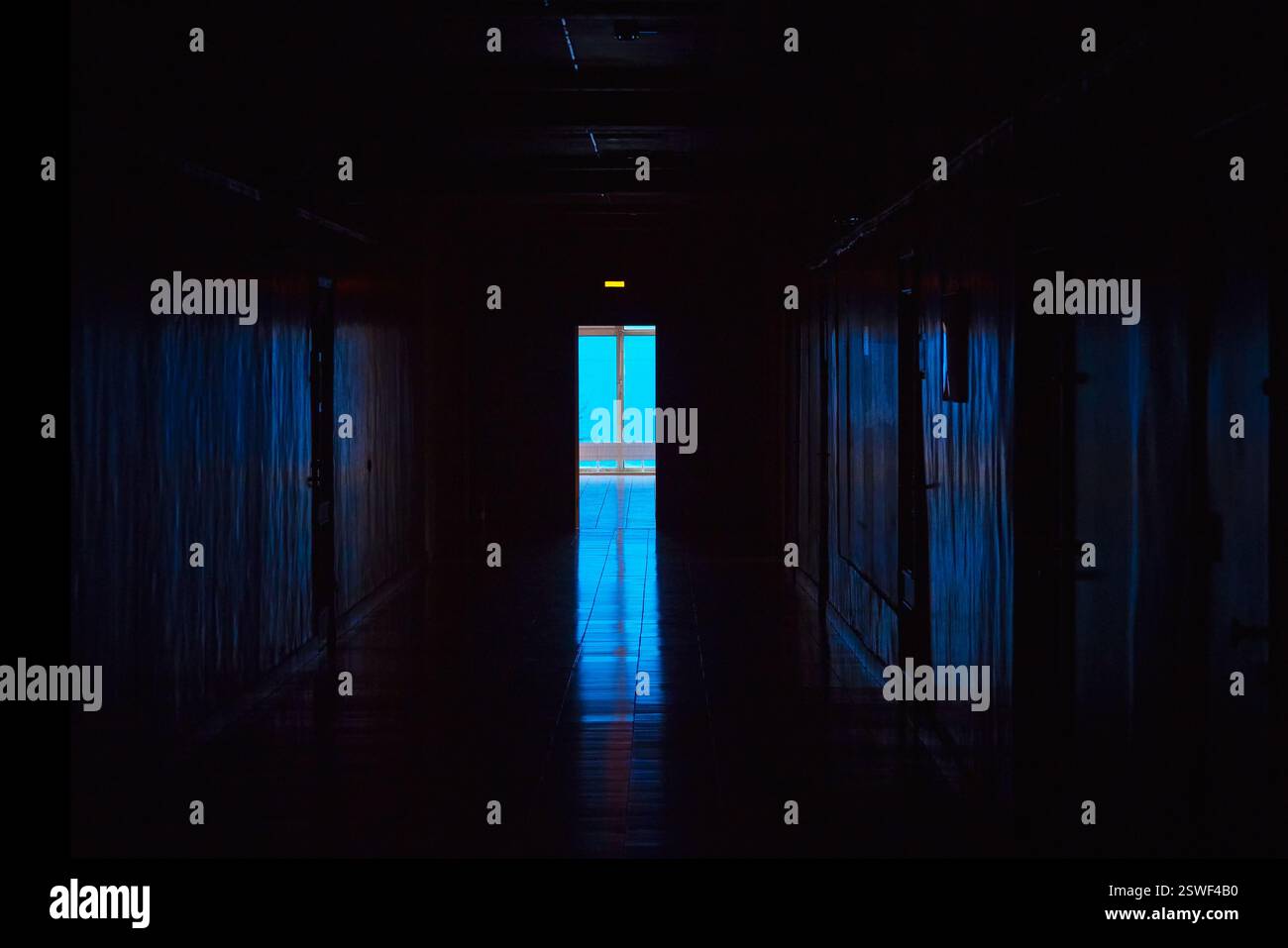 Luce blu alla fine di un corridoio buio. Fine del tunnel buio con luce blu magica. Corridoio oscuro vuoto nel laboratorio dell'ospedale. Foto Stock