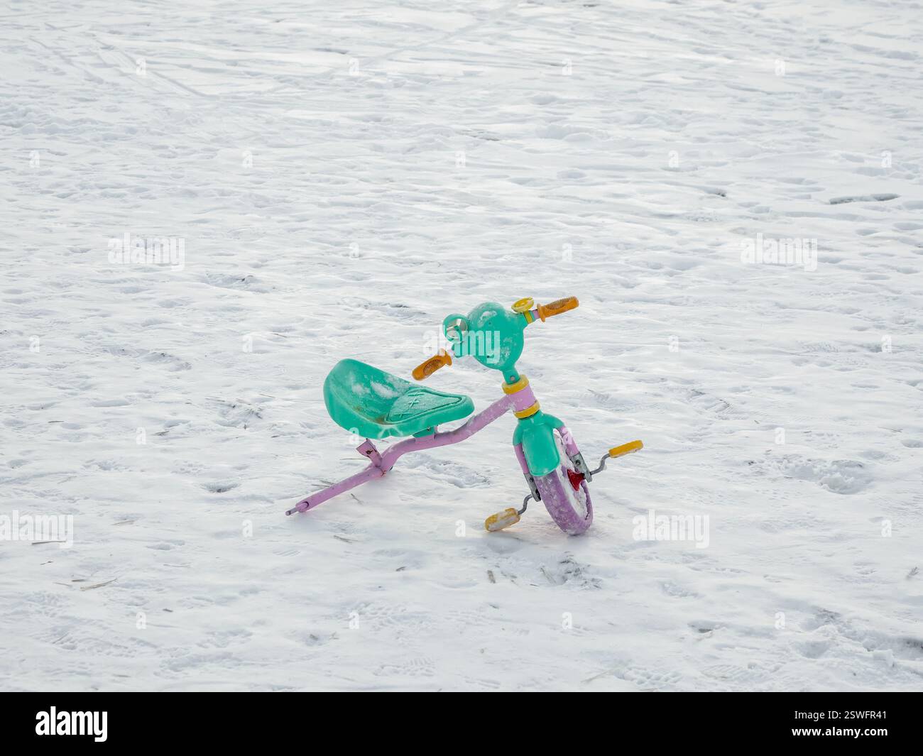 Bici per bambini rotta abbandonata nella neve. La fine delle vacanze. Foto Stock
