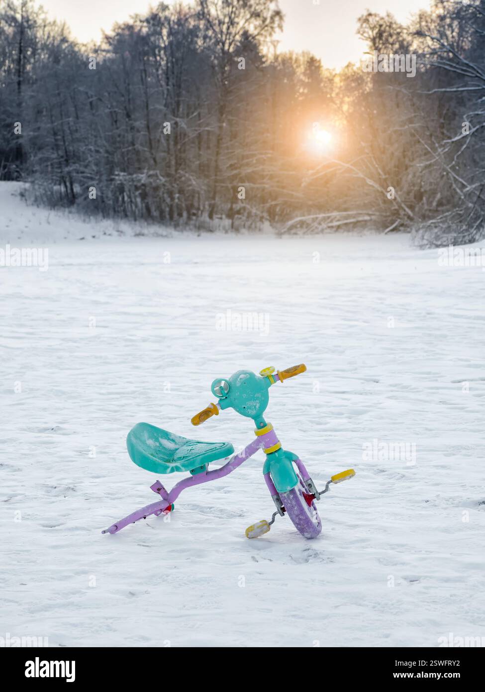 Bici per bambini rotta abbandonata nella neve. La fine delle vacanze. Foto Stock