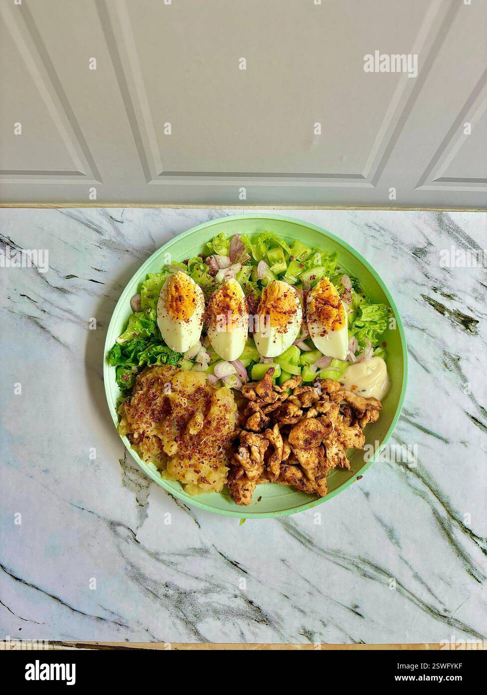 Un'insalata vivace e nutriente con pollo alla griglia, uova sode speziate e verdure fresche, perfetta per un pasto sano e per fotografare cibo Foto Stock