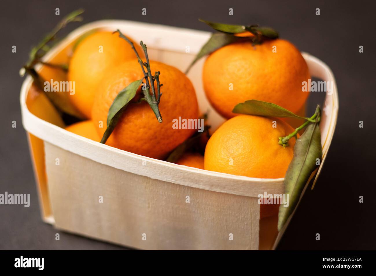 Primo piano di frutta mandarina in una scatola di legno su sfondo grigio Foto Stock