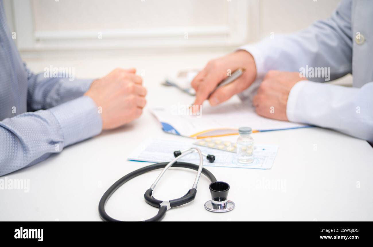 Medico discute problemi di salute con un paziente, rivedendo note e farmaci in uno studio medico durante un appuntamento. Foto Stock