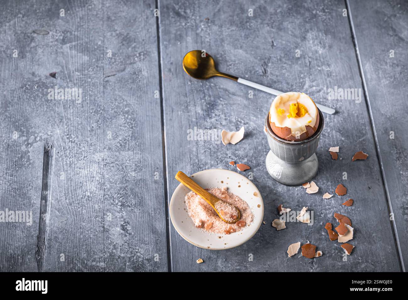 Uovo bruno sodo in cui la parte superiore viene tagliata in una tazza grigia su sfondo grigio, copiare lo spazio Foto Stock