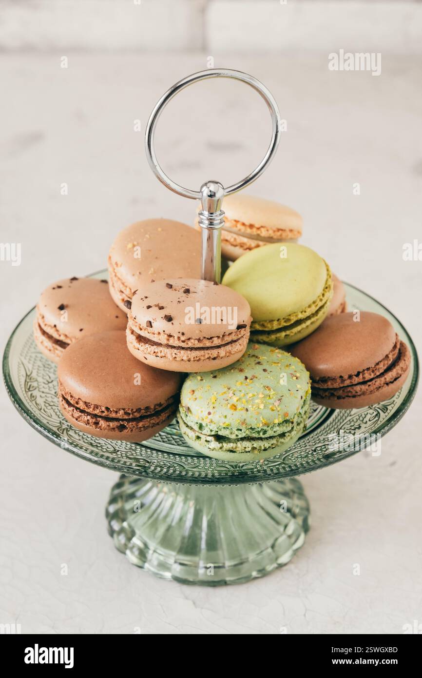 Macaron francesi colorati su un'etagere di vetro. Pasticcini, dessert e dolci. Foto verticale. Foto Stock