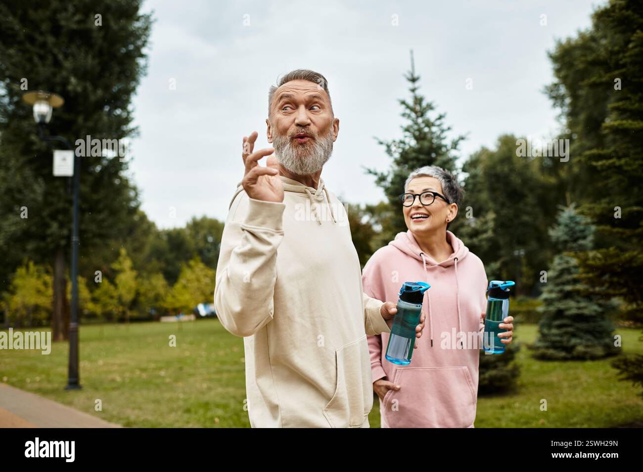 Una coppia amorevole cammina mano nella mano, condividendo risate e calore in un tranquillo parco. Foto Stock