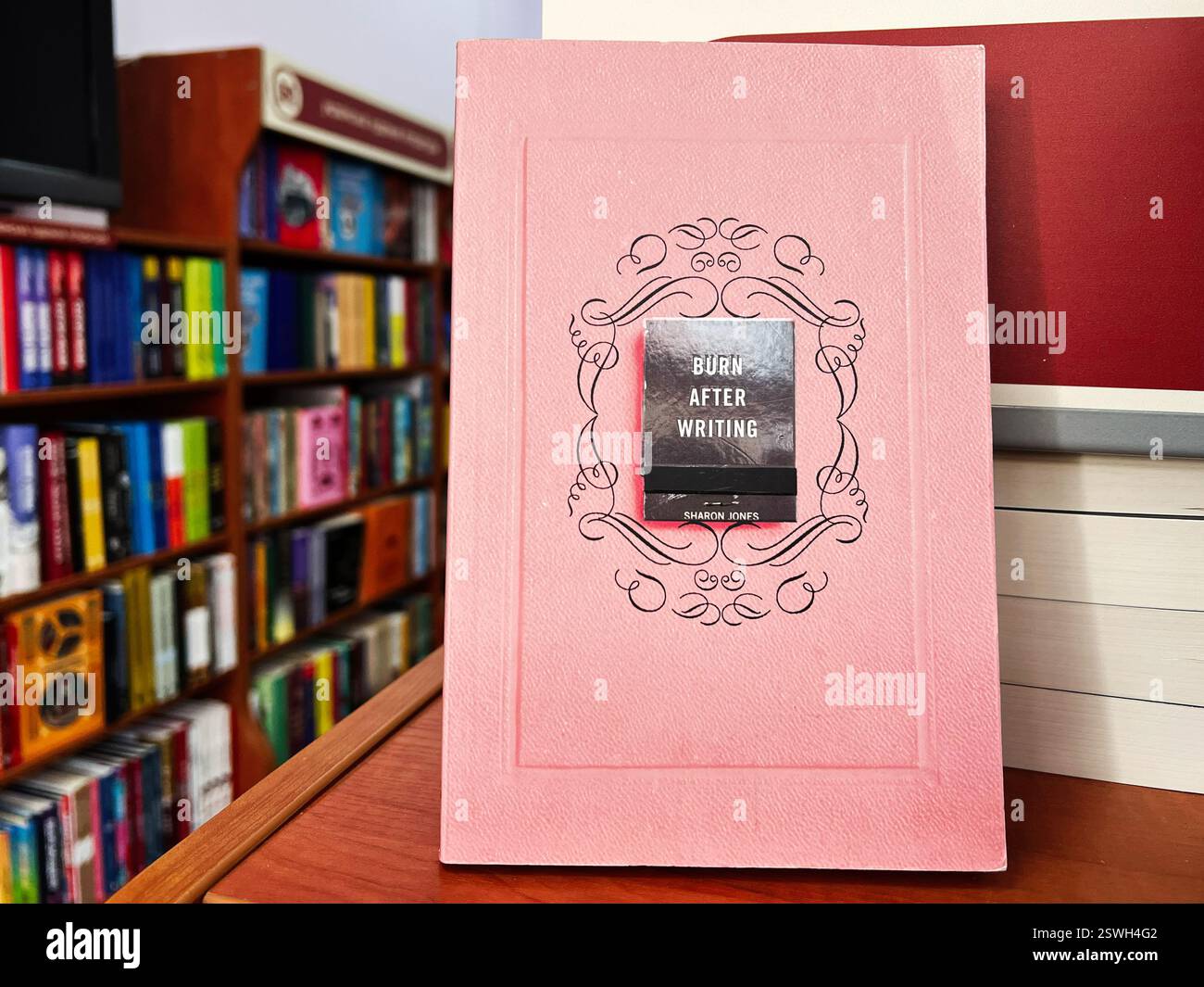 Leopoli, Ucraina - 20 febbraio 2025: Brucia dopo aver scritto Sharon Jones. Un libro rosa collocato su una superficie di legno su uno sfondo da libreria Foto Stock