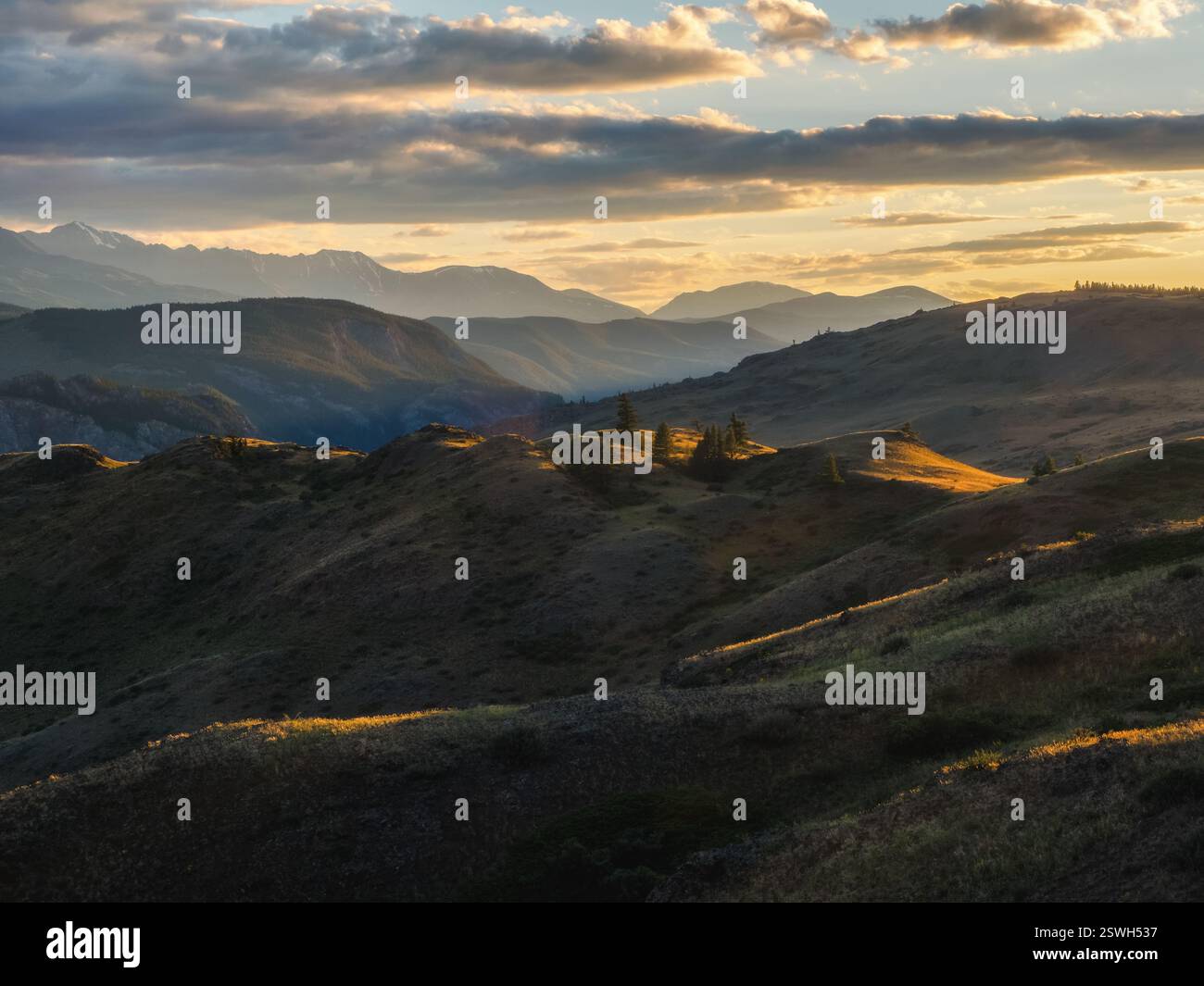 Le colline autunnali di montagna sono illuminate dal sole del tramonto. Sole dell'alba, splendente tra le montagne Foto Stock