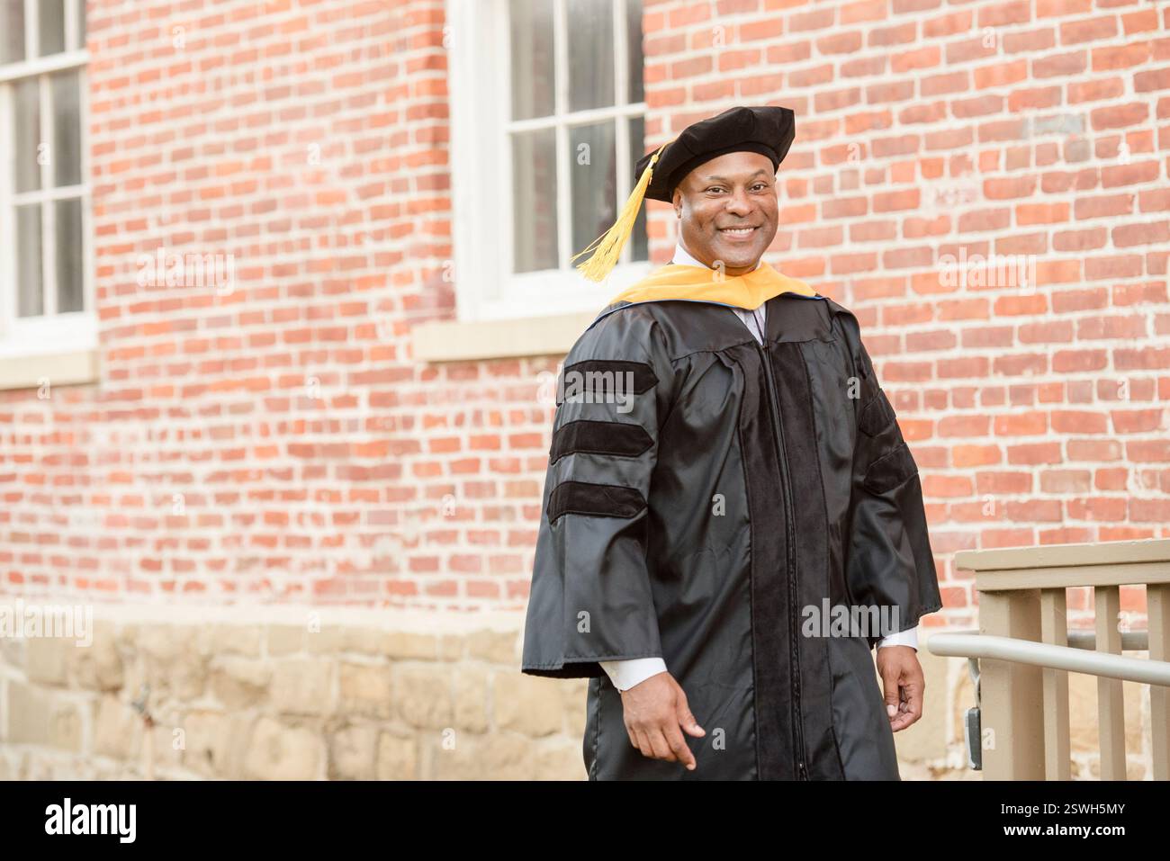 Orgoglioso laureato in insegne accademiche, che celebra una pietra miliare Foto Stock