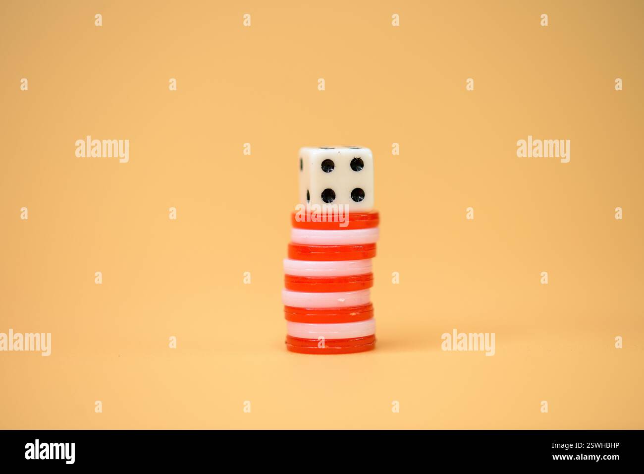 Una pila di fichette da poker con dadi sullo sfondo arancione, che simboleggiano la possibilità, i giochi e l'intrattenimento, tiddlywinks Foto Stock