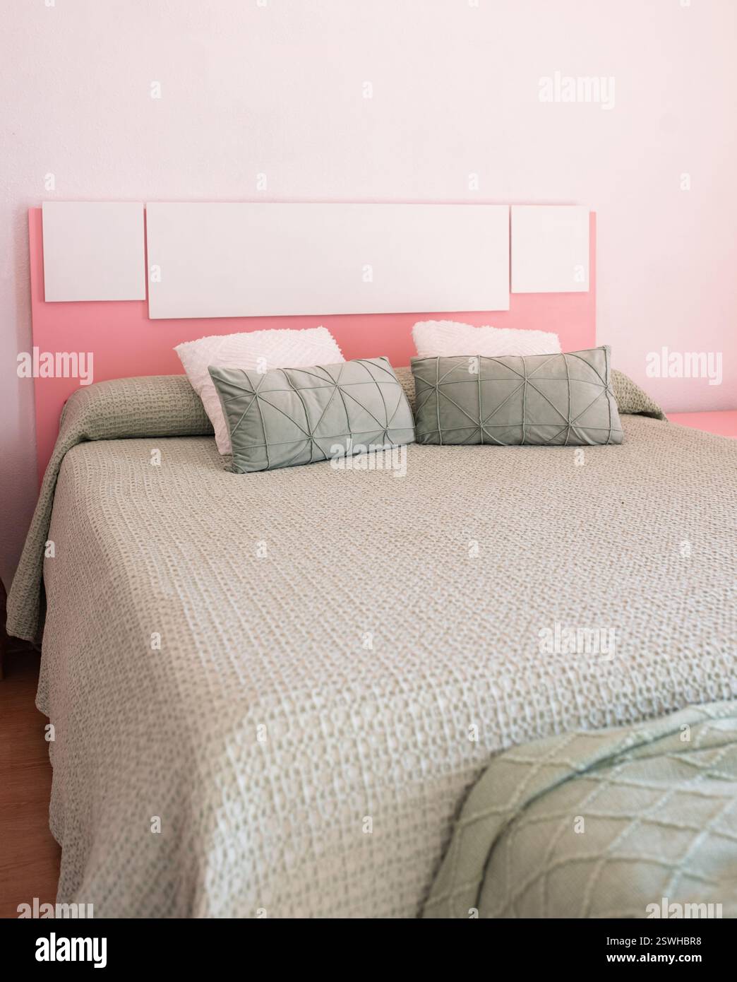 Letto matrimoniale con cuscini all'interno della moderna camera da letto nell'appartamento mansardato in stile color chiaro degli appartamenti costosi. Foto Stock