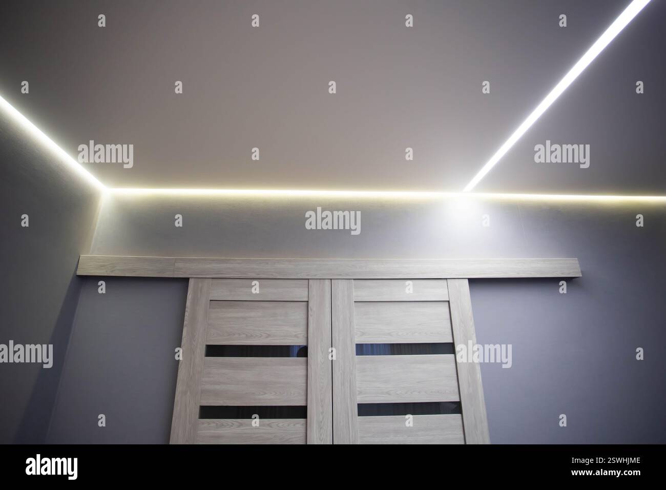 Splendido soffitto allungato moderno con linee LED gialle lungo il perimetro. Elegante soffitto di design nella hall, decorazioni Foto Stock