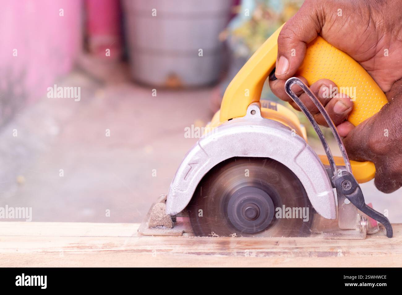 Persona che taglia il legno con una macchina per il taglio del legno con un'area circostante piena di polvere Foto Stock
