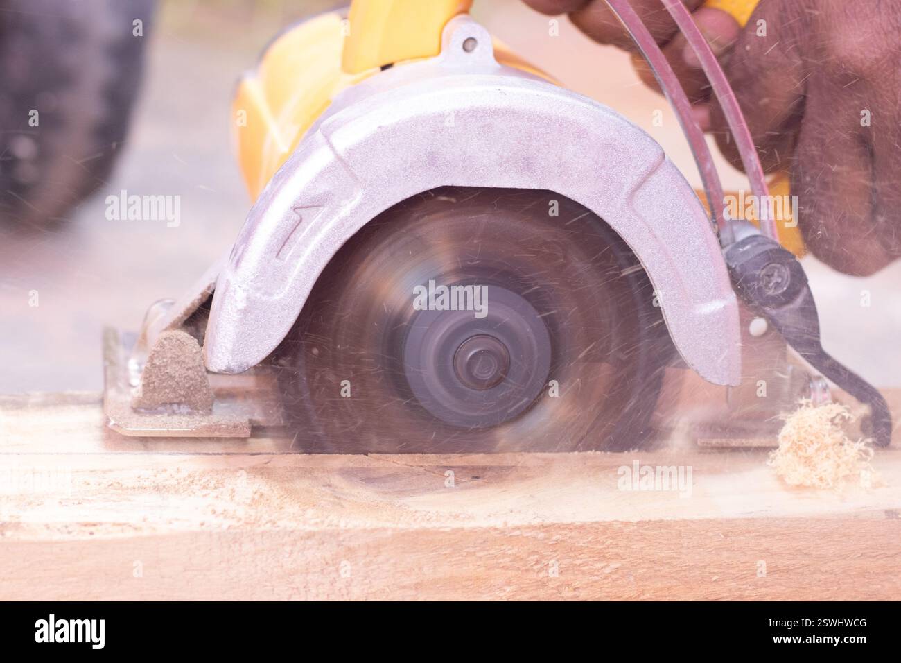 Persona che taglia il legno con una macchina per il taglio del legno con un'area circostante piena di polvere Foto Stock