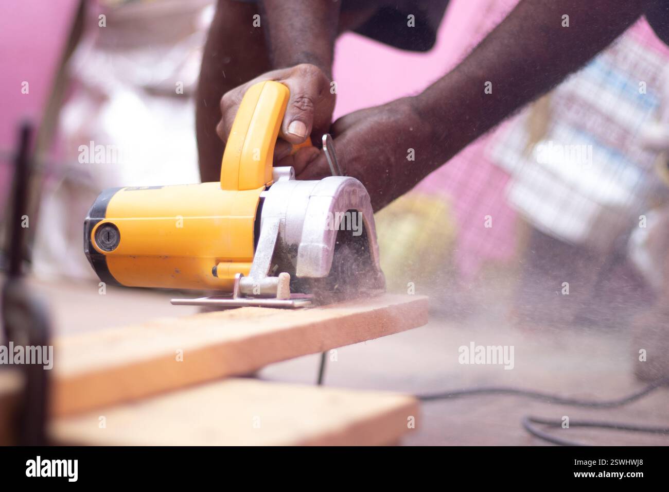 Persona che taglia il legno con una macchina per il taglio del legno con un'area circostante piena di polvere Foto Stock