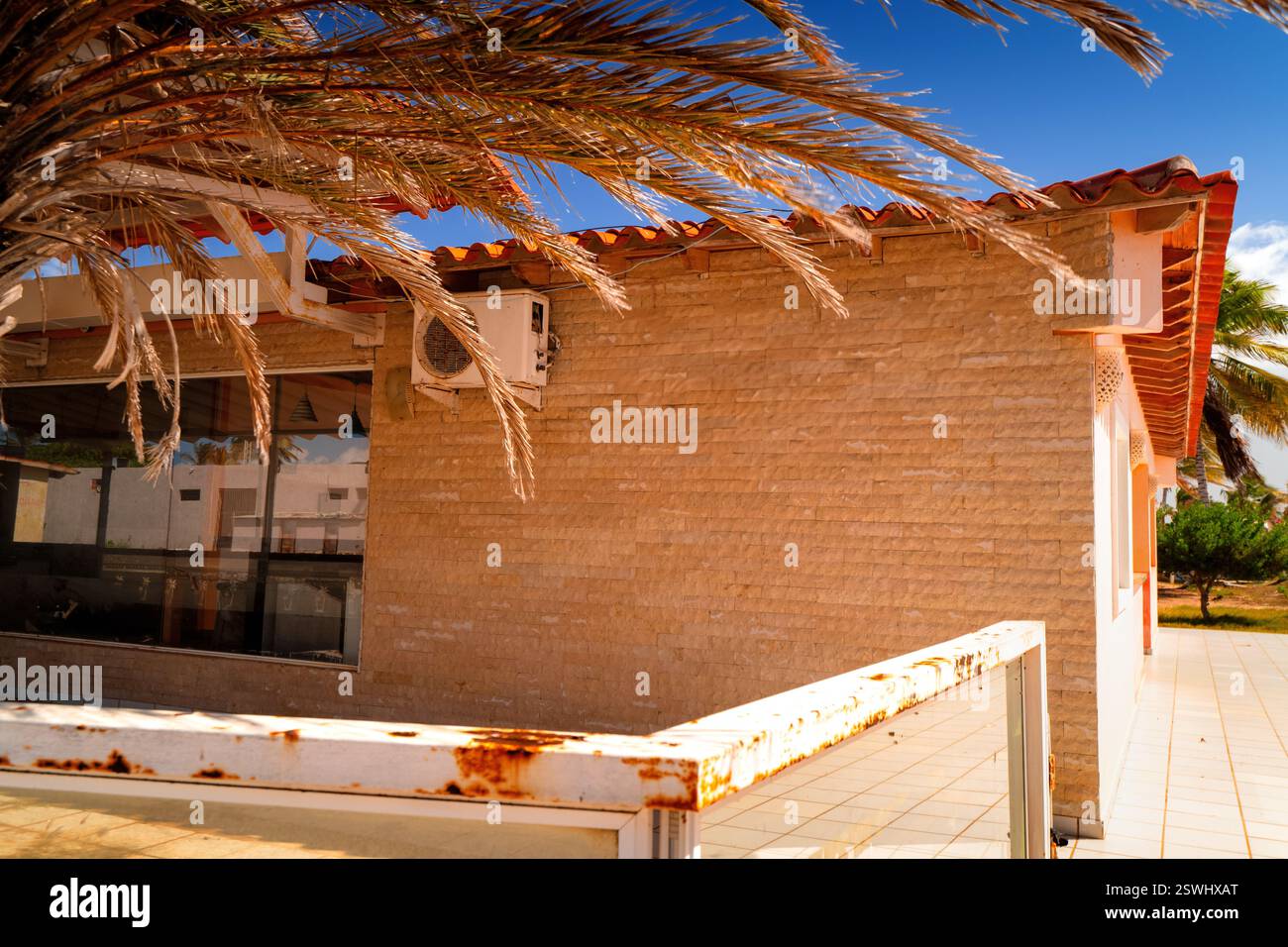 Costa sudamericana. Vecchio edificio sotto le palme. Isola di Coche, Venezuela. Una classica vista delle vacanze. Foto Stock