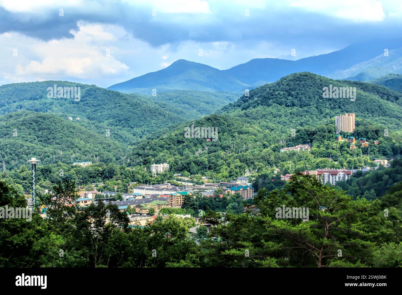 Catena montuosa con una città nella valle. La città è circondata da alberi e dispone di alcuni edifici Foto Stock