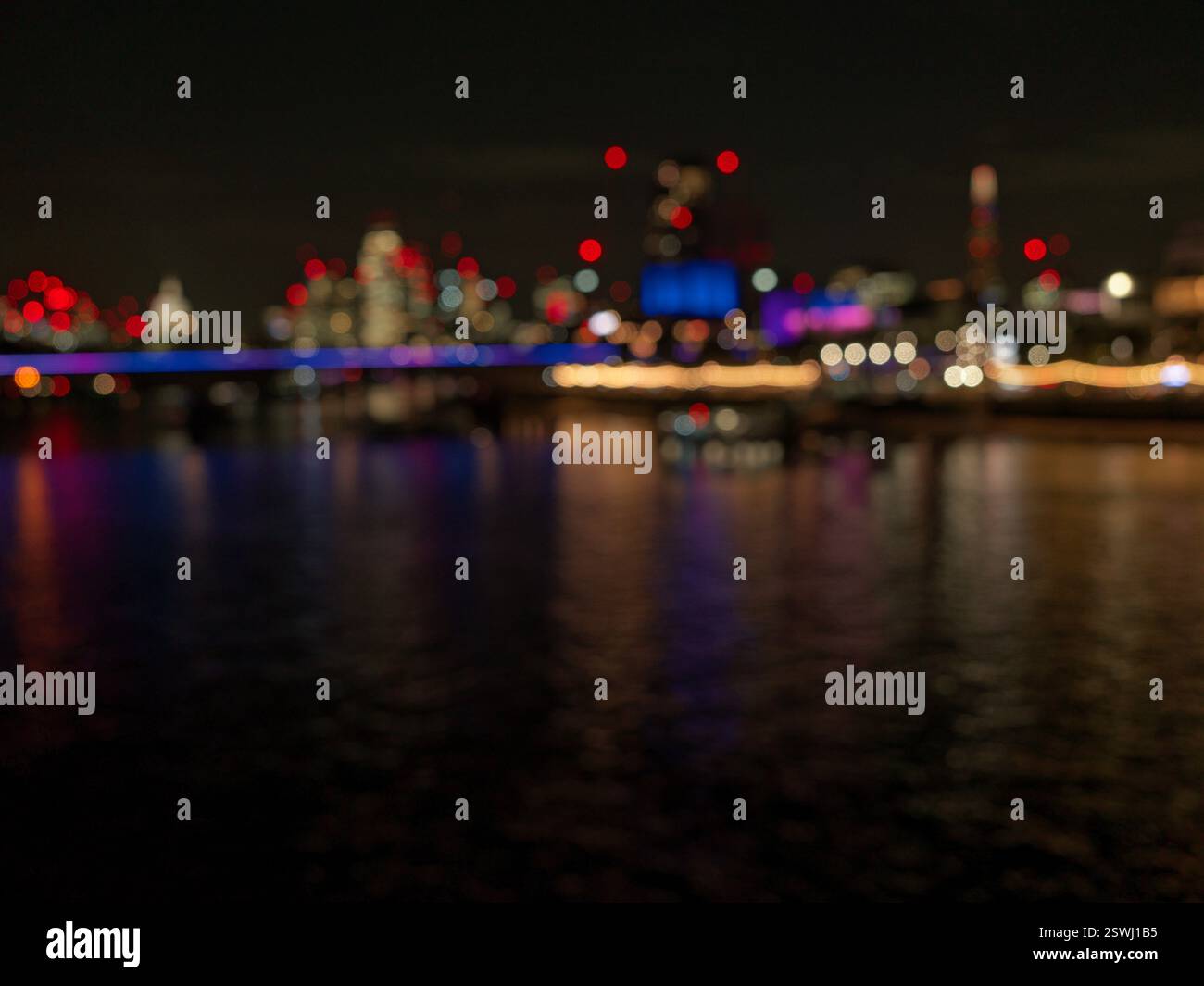 Il Tamigi e gli edifici di Londra adiacenti al Waterloo Bridge di notte. Intenzionalmente fuori fuoco. Foto Stock