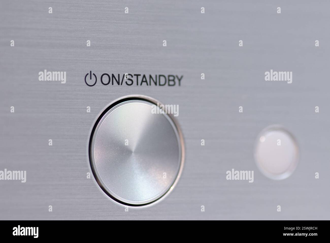 Visualizzazione dettagliata di un pulsante di accensione metallico lucido con etichetta "On/Standby", che mostra i moderni componenti elettronici e il design minimalista. Foto Stock