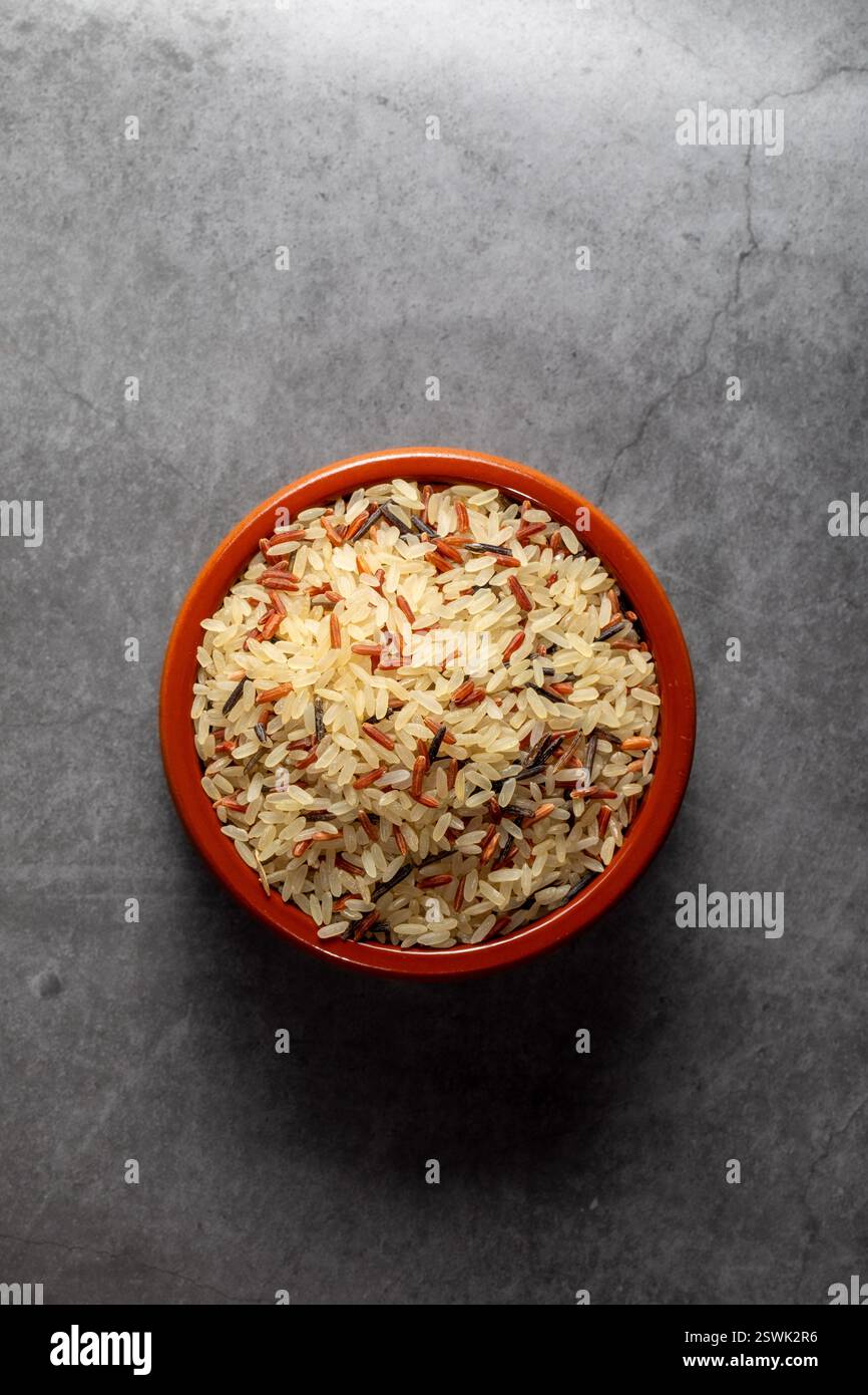 Ciotola in terracotta piena di riso selvatico rosso lungo su un ripiano della cucina in una fotografia zenithal Foto Stock