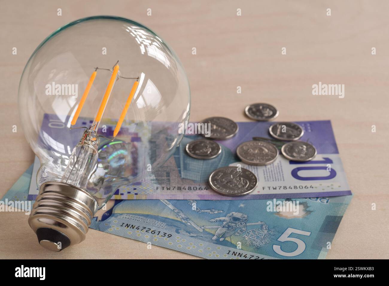 Lampadina a LED con moneta e monete in carta canadese, concetto di risparmio energetico Foto Stock