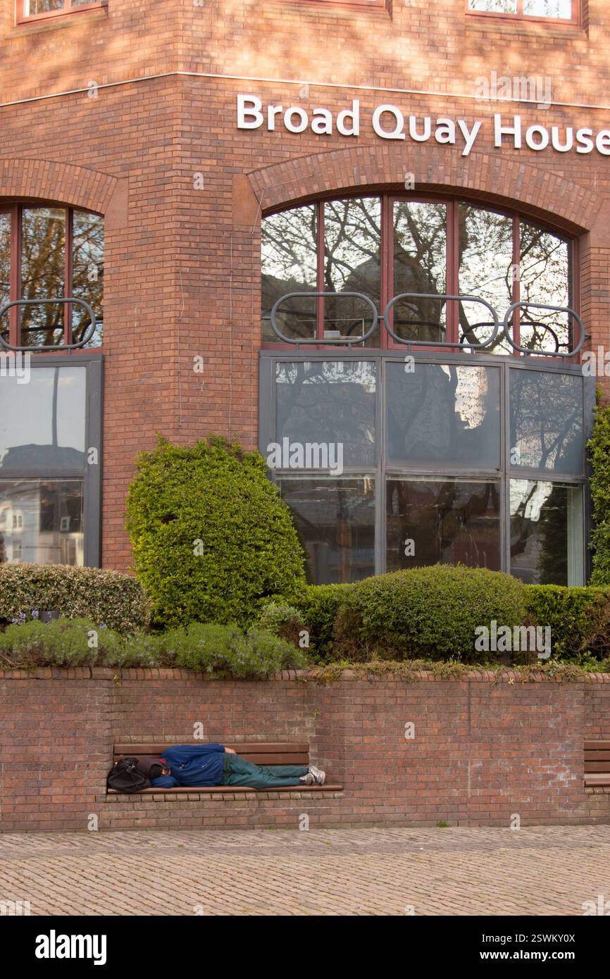 Persona che dorme sulla panchina fuori Broad Quay House, Bristol, Regno Unito. Foto Stock