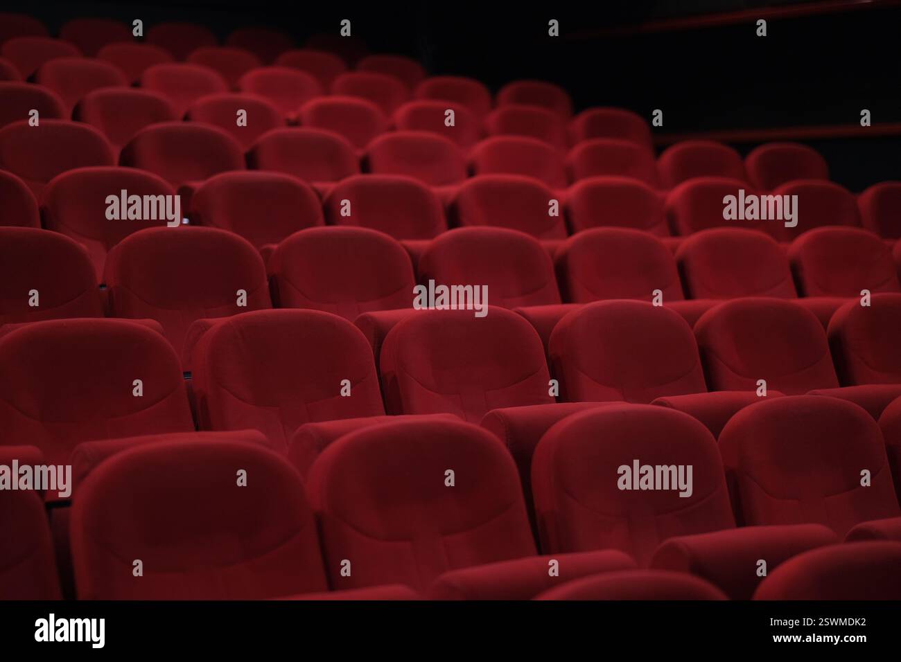 File di sedili in velluto rosso non occupati in un teatro creano profondità e interesse visivo posti a sedere classici al cinema Foto Stock