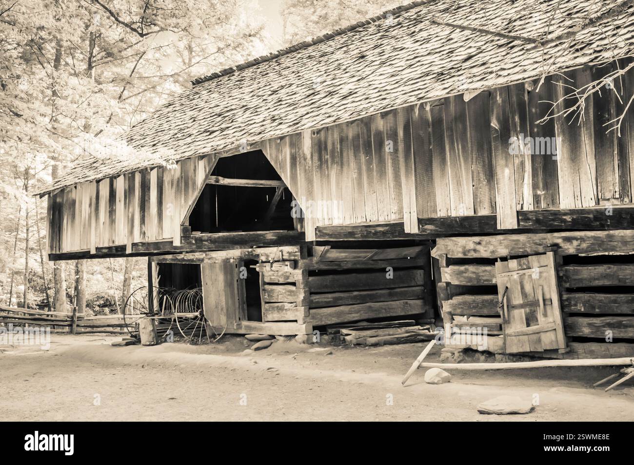 Stalla con una ruota a terra. Il fienile è vecchio e ha molto legno Foto Stock