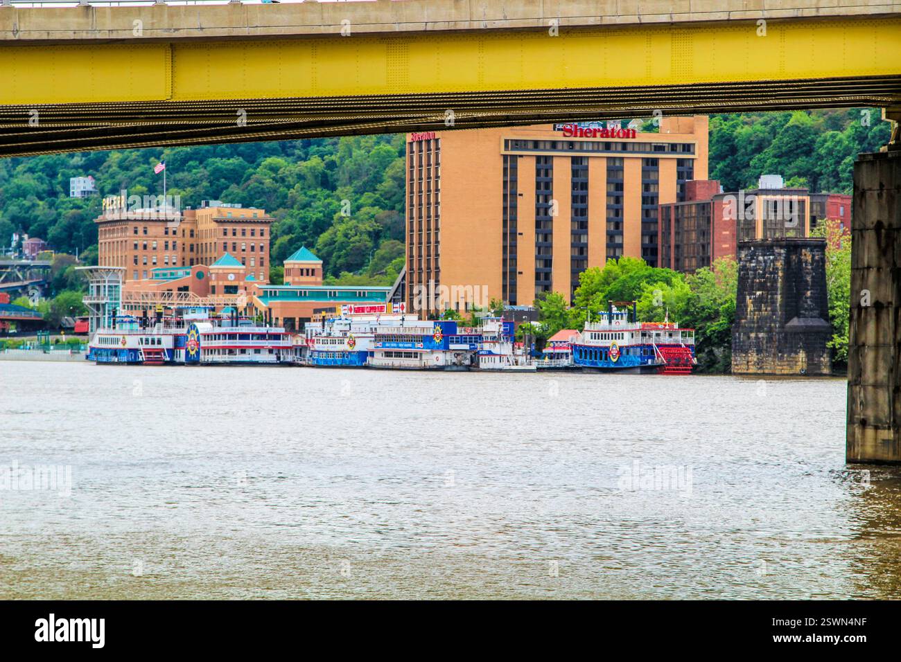 Le barche colorate sono attraccate lungo la riva del fiume con gli edifici della città in vista. Foto Stock