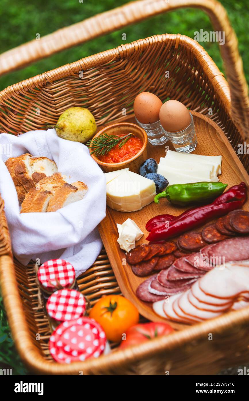 Un cestino da picnic pieno di prelibatezze salate, prodotti freschi e pane artigianale. Foto Stock