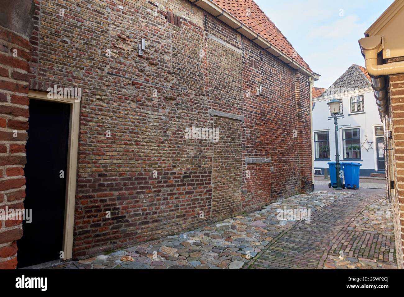 Hasselt, Paesi Bassi: Uno stretto vicolo storico con marciapiedi di ciottoli, un arco in mattoni e una vecchia casa olandese vicino all'acqua. Foto Stock