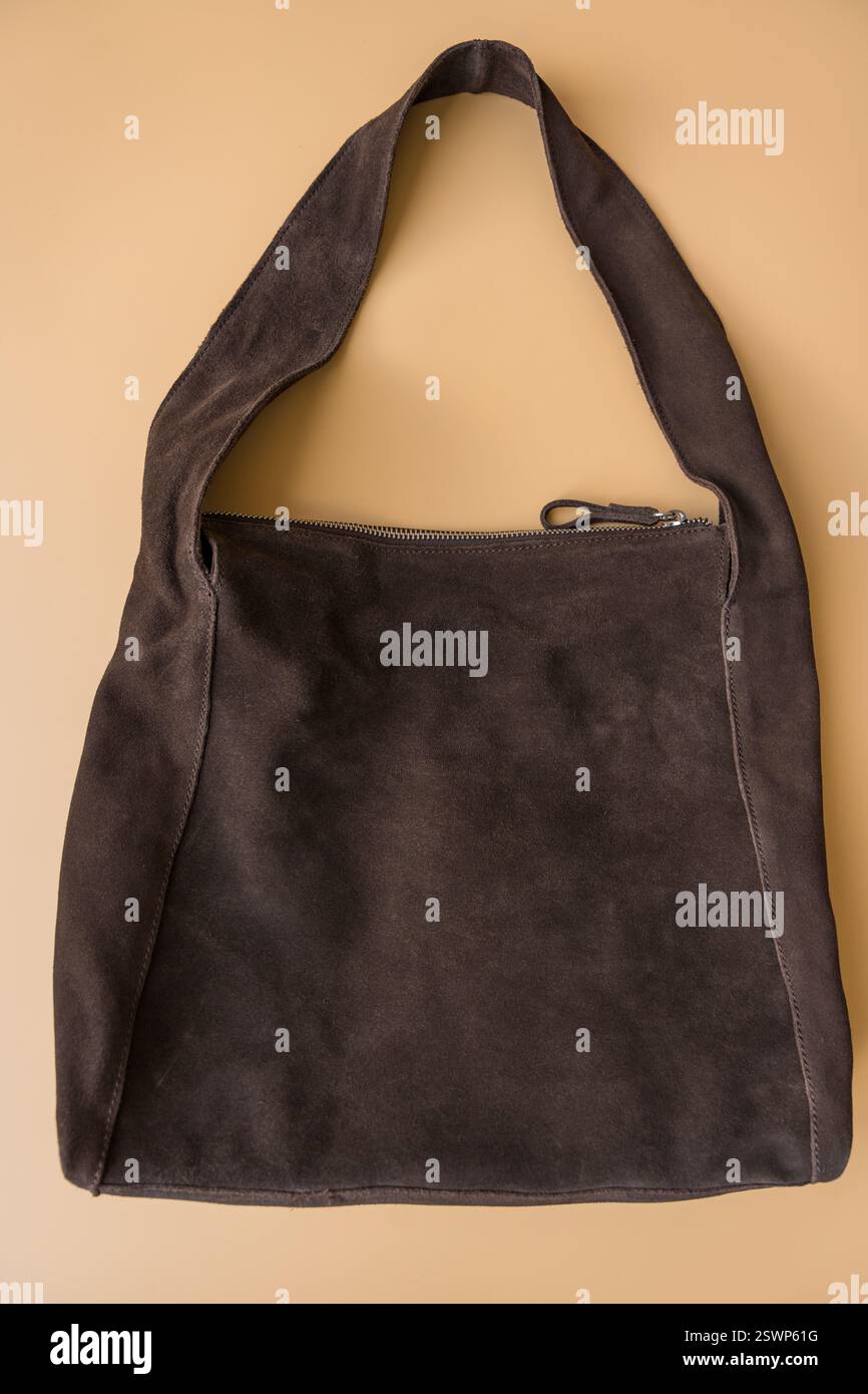 Borsa a spalla minimalista in pelle scamosciata marrone su sfondo pastello Foto Stock