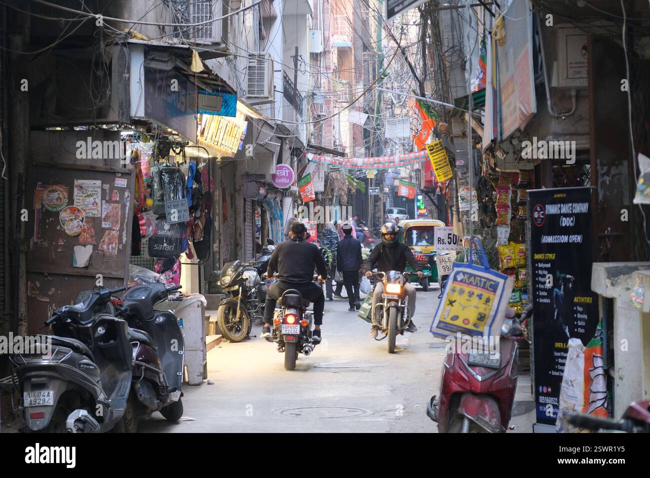 Gli uomini in moto percorrono uno stretto vicolo nella vivace area di Safdarjung enclave della capitale indiana Delhi Foto Stock