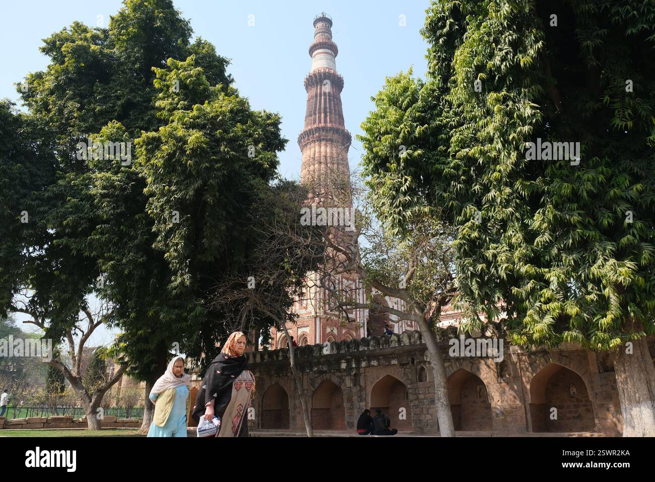 Le donne camminano nei terreni di Qutub Minar, un popolare sito patrimonio del XII secolo nella capitale indiana Delhi Foto Stock