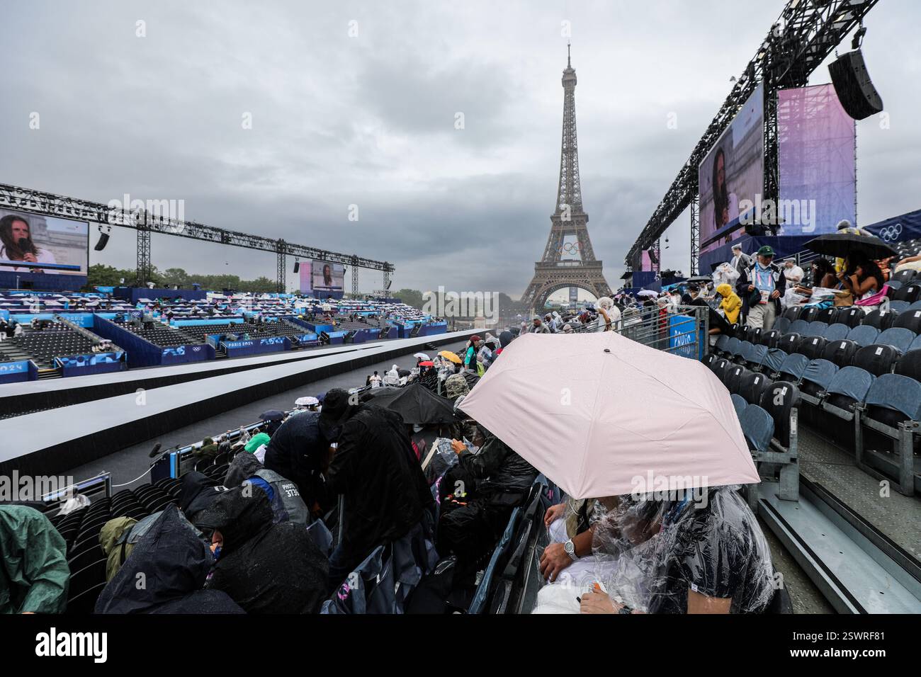 26 luglio 2024 - Parigi, Francia: Gli spettatori indossano il cappotto antipioggia e tengono in mano gli ombrelli come cerimonia di apertura delle Olimpiadi di Parigi 2024, la prima ad Olimpica Foto Stock