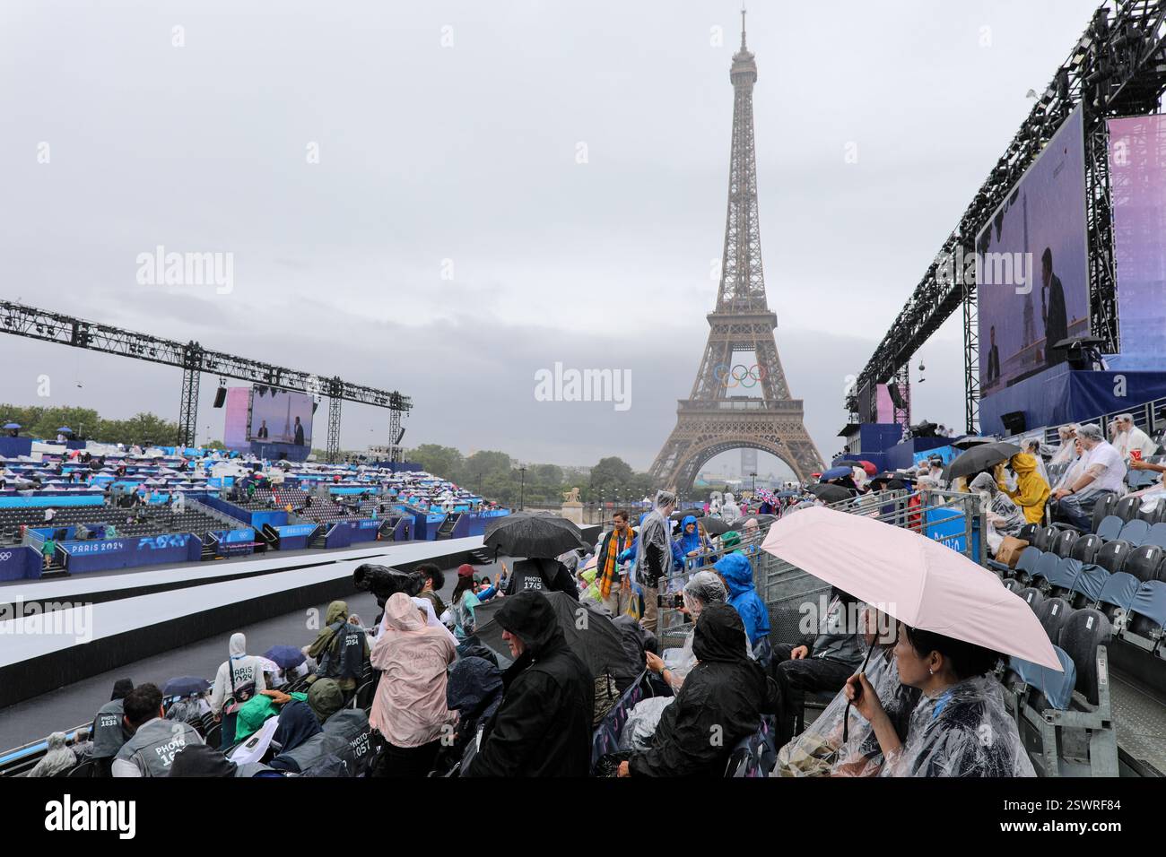 26 luglio 2024 - Parigi, Francia: Gli spettatori indossano il cappotto antipioggia e tengono in mano gli ombrelli come cerimonia di apertura delle Olimpiadi di Parigi 2024, la prima ad Olimpica Foto Stock