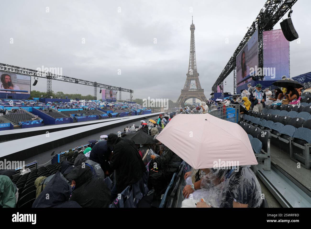 26 luglio 2024 - Parigi, Francia: Gli spettatori indossano il cappotto antipioggia e tengono in mano gli ombrelli come cerimonia di apertura delle Olimpiadi di Parigi 2024, la prima ad Olimpica Foto Stock