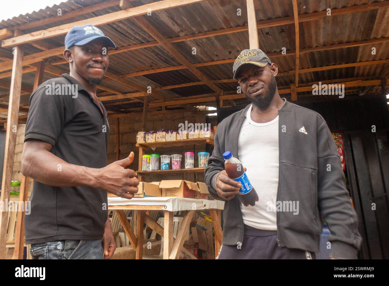 una serie di foto candide di proprietari maschi di piccole imprese in africa che servono i clienti, utilizzando smartphone e macchine pos mentre vendono generi alimentari e prodotti alimentari Foto Stock