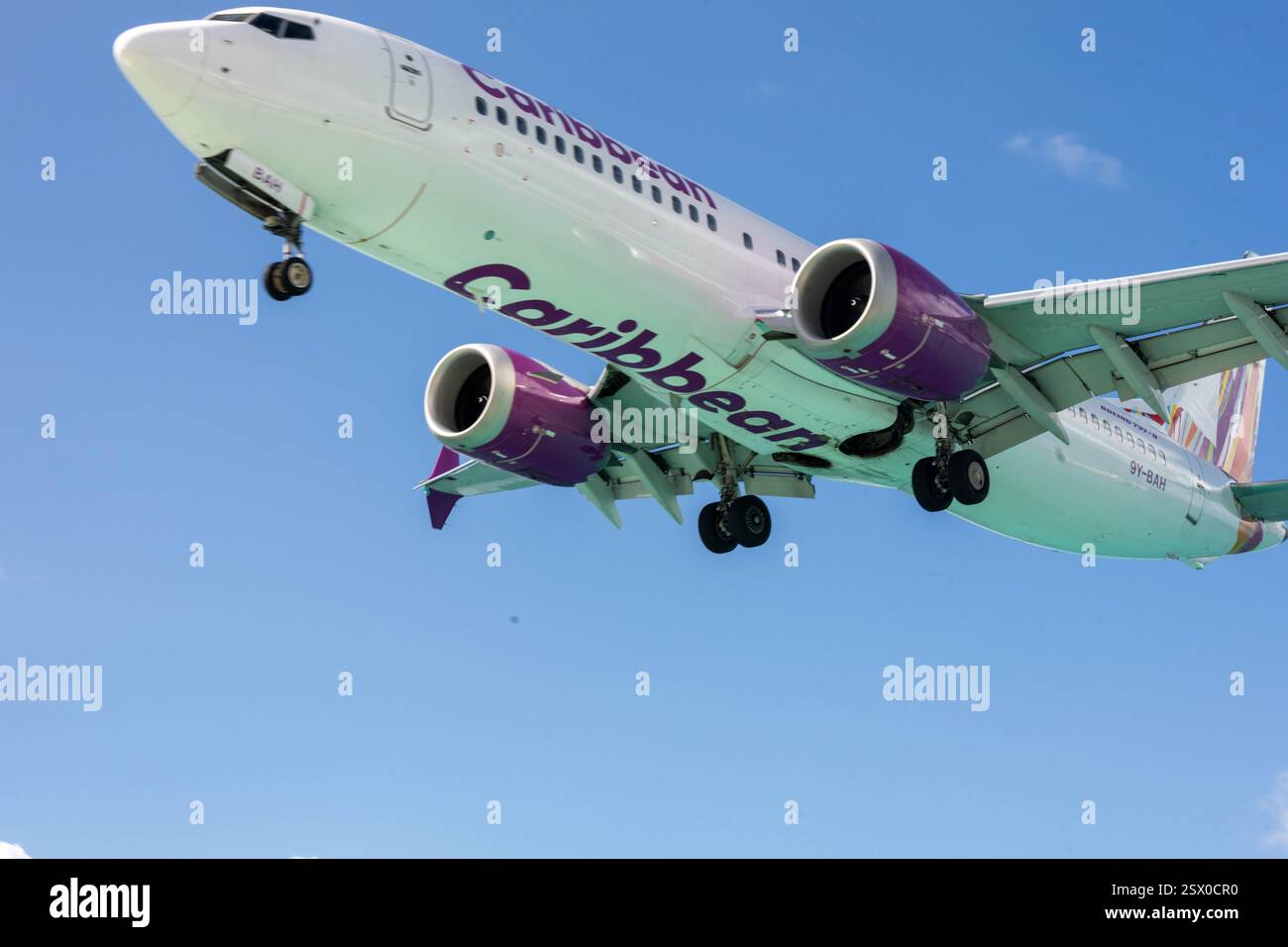 Un Boeing 737-8 MAX operato da Caribbean Airlines sorvola Maho Beach presso l'aeroporto internazionale Princess Juliana Saint Martin Caribbean, famoso in tutto il mondo Foto Stock