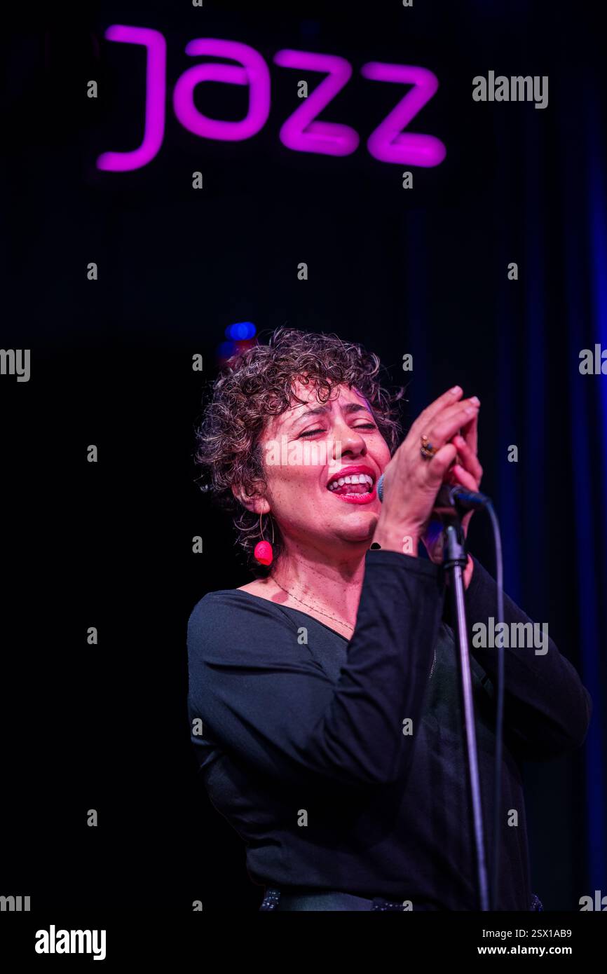 Cantante che esegue appassionatamente musica jazz sul palco in un locale notturno. Foto Stock