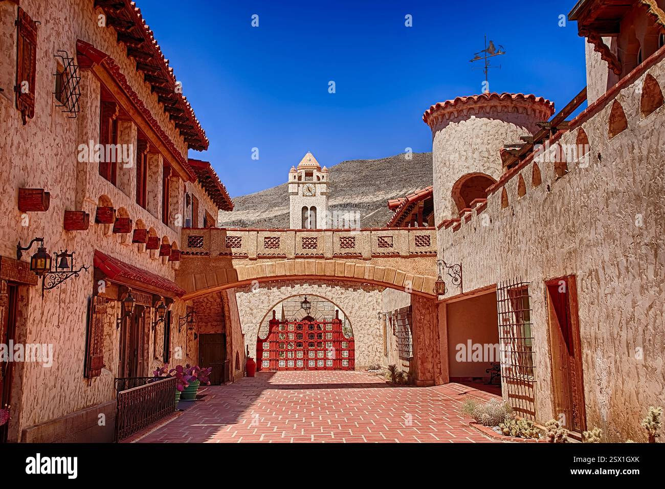 Strada stretta con un cancello rosso e un edificio con una torre dell'orologio. Il cancello è aperto Foto Stock