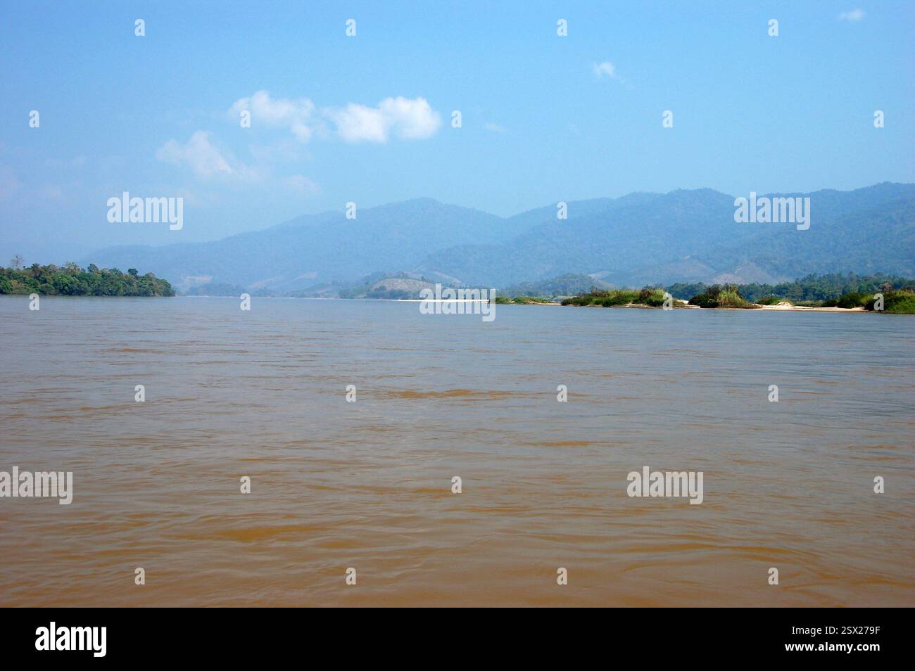 Paesaggio del fiume Mekong al Triangolo d'Oro, nel nord della Thailandia, con colline verdi, cielo blu e acque calme lungo il confine di tre paesi Foto Stock