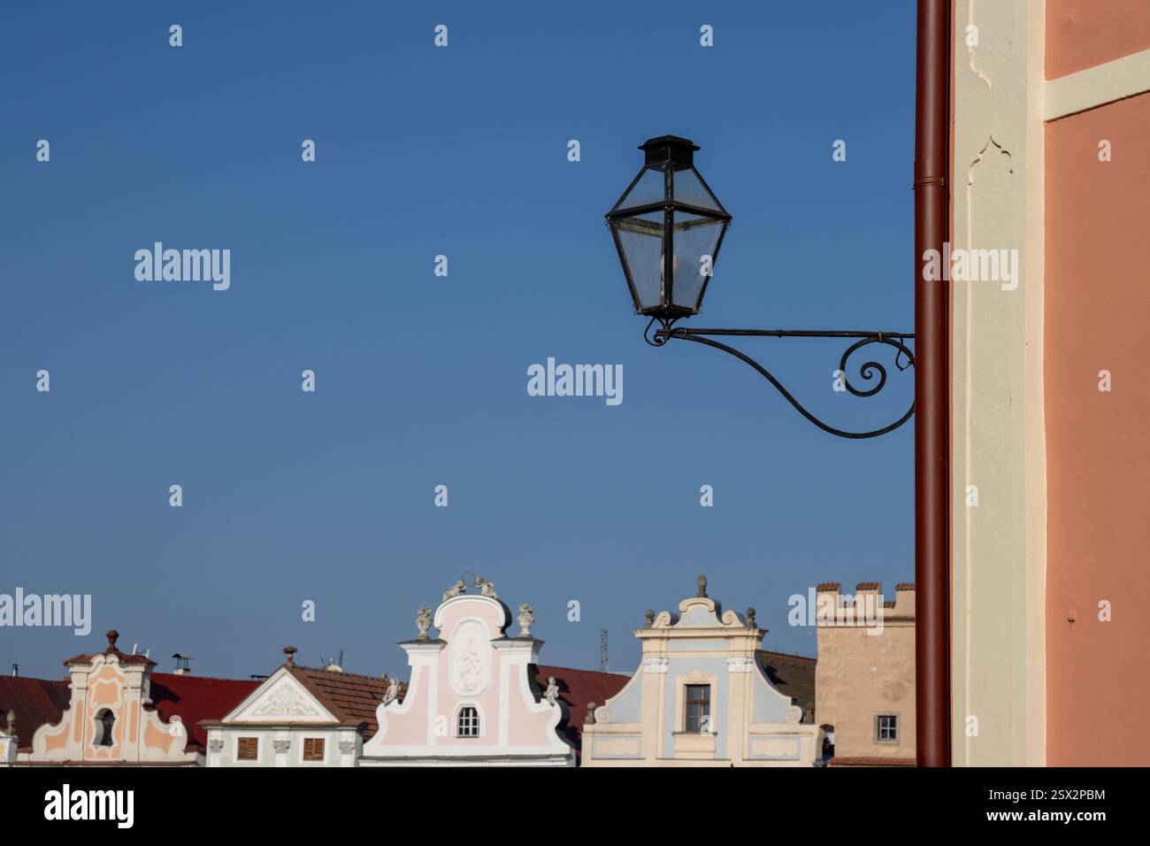 Lanterna nera in un angolo di una casa. Parti principali e tetti di case storiche colorate sulla piazza. Cielo blu brillante. Telc, repubblica Ceca. Foto Stock