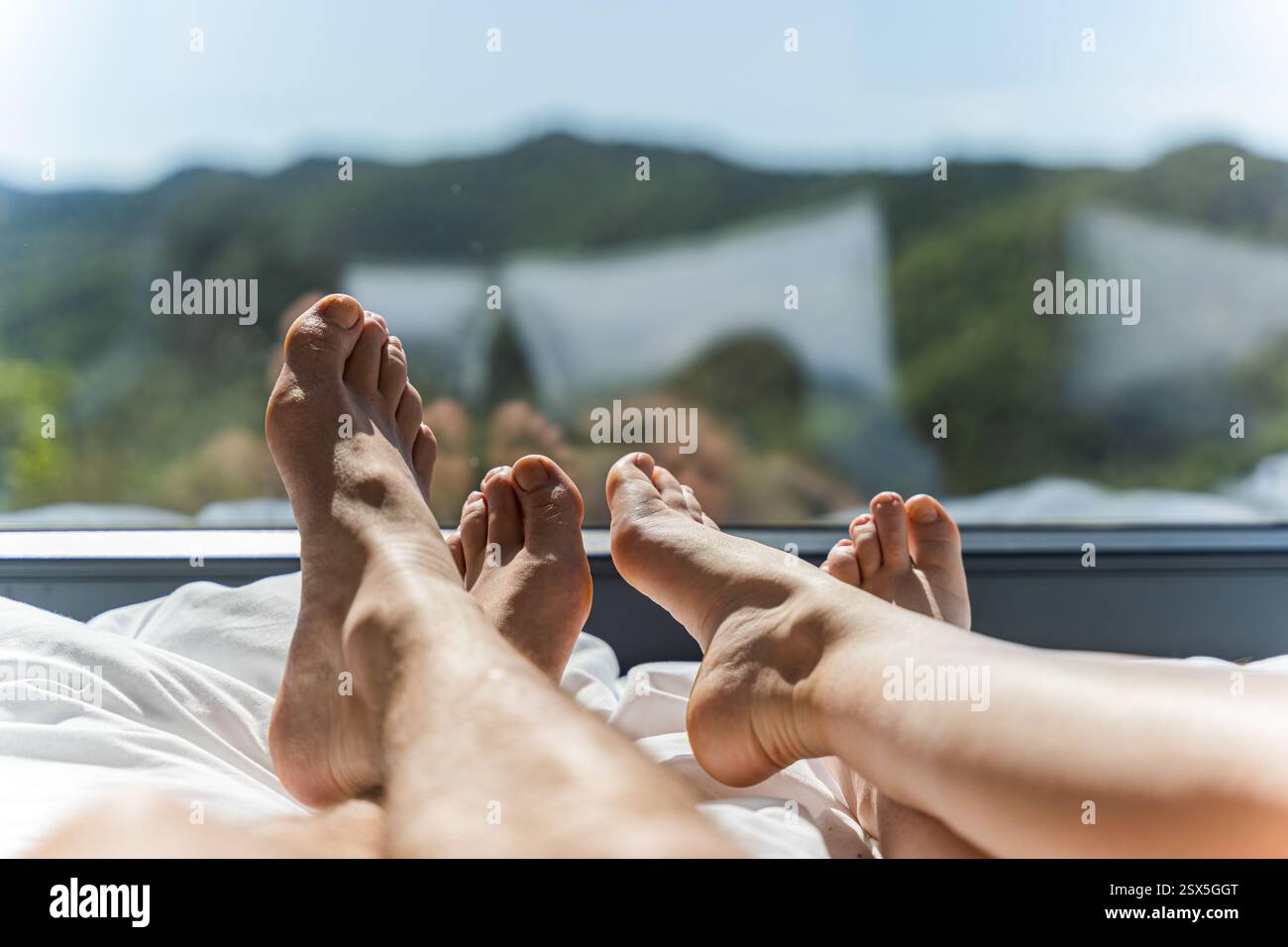 Un momento romantico di coppia che si rilassa nel letto in una cabina di legno con vista sulle montagne Foto Stock