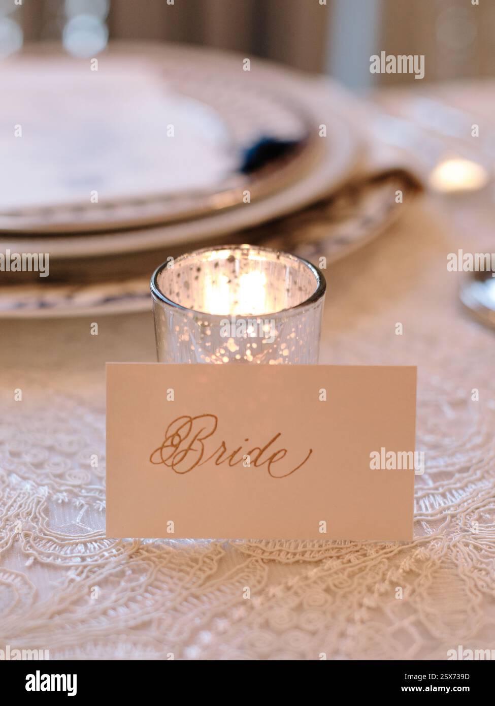 Un delizioso tavolo presenta una carta da sposa e una candela tremolante, che creano un'atmosfera romantica. Foto Stock