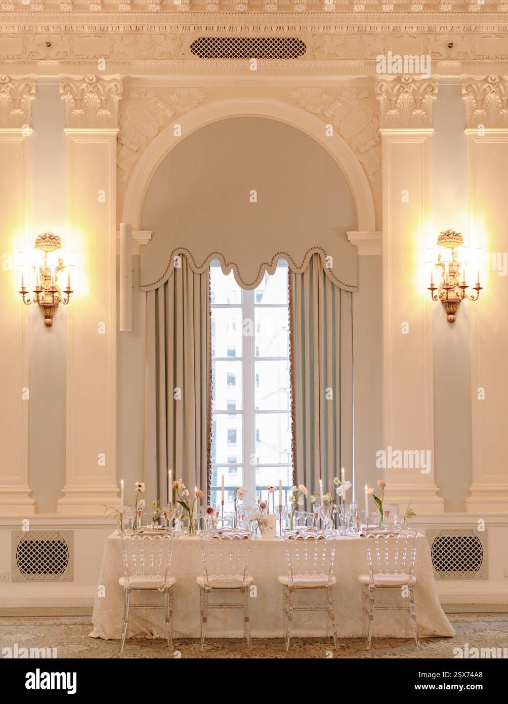 Un tavolo da pranzo elegantemente disposto e' allestito in una sofisticata sala caratterizzata da luci soffuse e decor decorato. Foto Stock