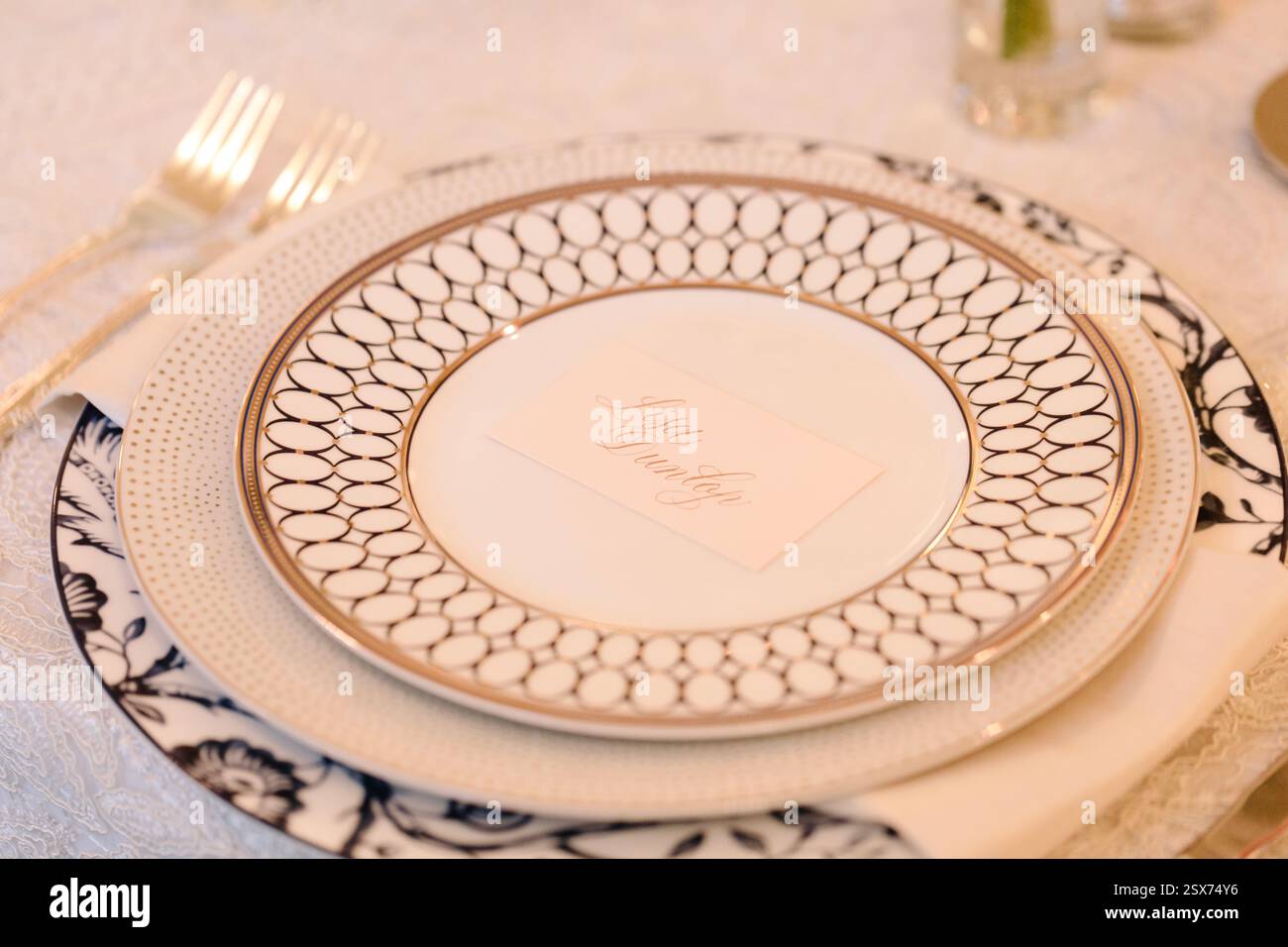 Un tavolo da pranzo splendidamente organizzato presenta piatti delicati e un biglietto da visita, che mostra eleganza per un pasto festivo. Foto Stock